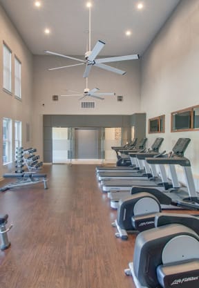 a fitness center with cardio equipment and windows on the wall at Stonelake at the Arboretum, Austin, TX, 78759