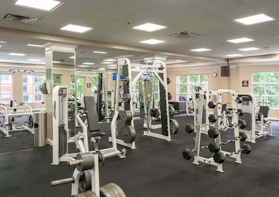 A gym with a variety of equipment including weight machines and free weights.