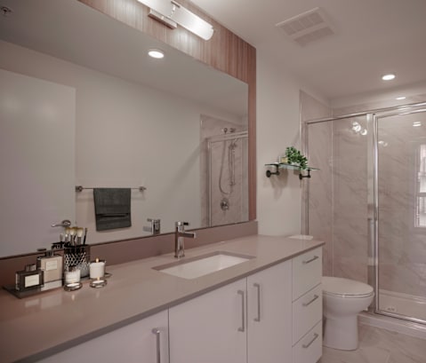 A bathroom with a sink, mirror, toilet, and shower.