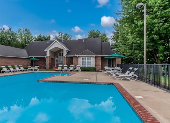 A large swimming pool in front of a house with a black fence around it.