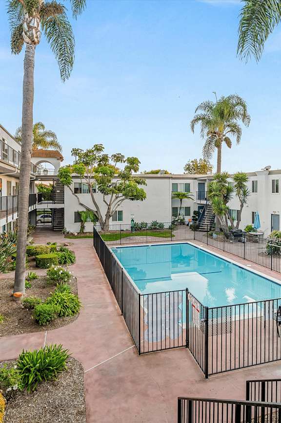 A small pool in a backyard with a house in the background.
