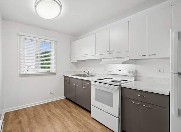 A kitchen with white appliances and wooden floors.