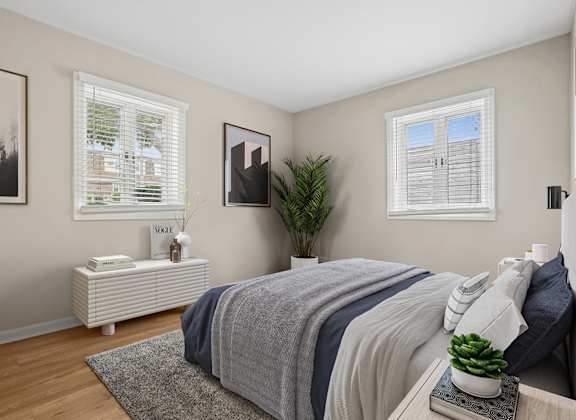 A bedroom with a bed, nightstand, and a plant.