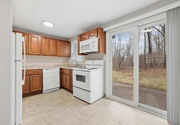 A kitchen with white appliances and wooden cabinets.