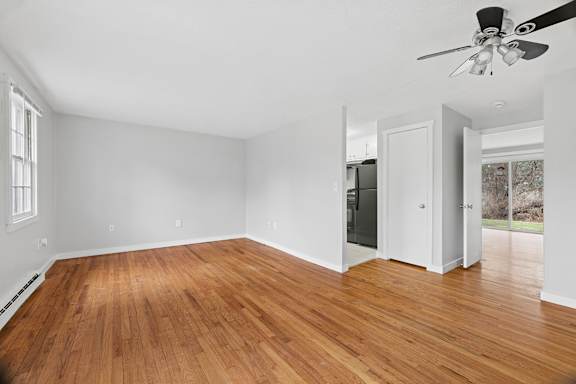 an empty living room with a sliding glass door and wood floors