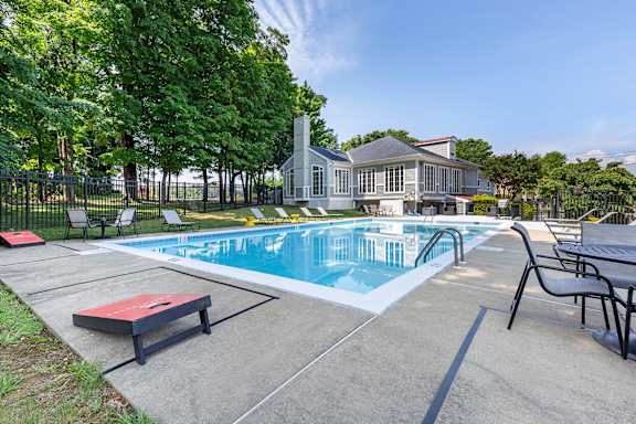 A pool with a table and chairs and a house in the background.