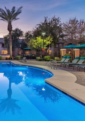 a swimming pool with chaise lounge chairs and umbrellas in front of a hotel