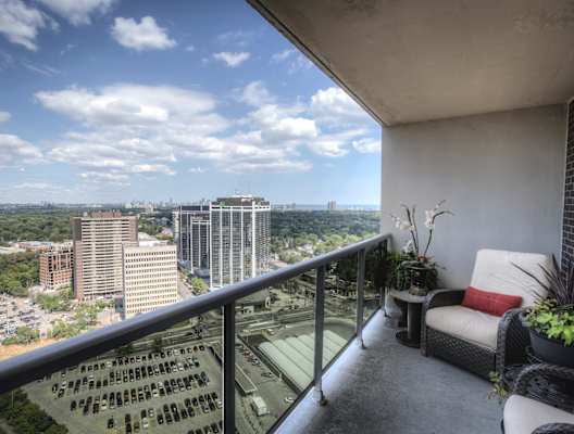A balcony with a couch and plants overlooking a cityscape.