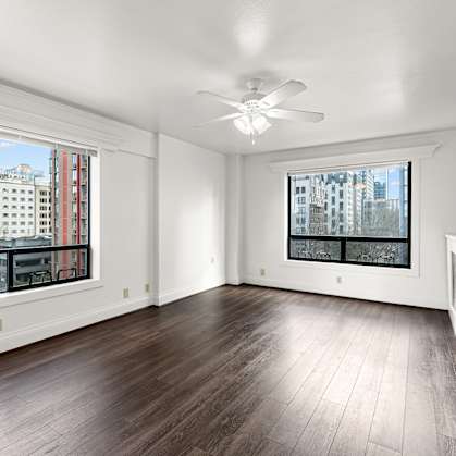 A room with a ceiling fan and two windows overlooking a cityscape. at The Exeter Apartments, Washington