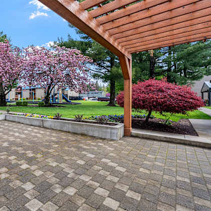 A patio with a wooden pergola and a brick patterned floor.