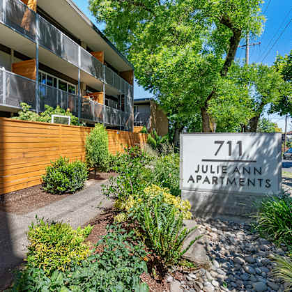 A sign for Julie Ann Apartments is in front of a building.