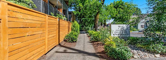 A pathway between two buildings with green plants on the sides.