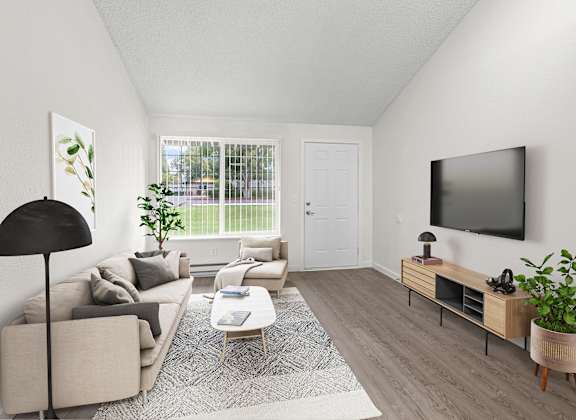 A living room with a grey couch, a black floor lamp, a white door, a grey rug, a wooden coffee table, a flat screen TV, and a plant.