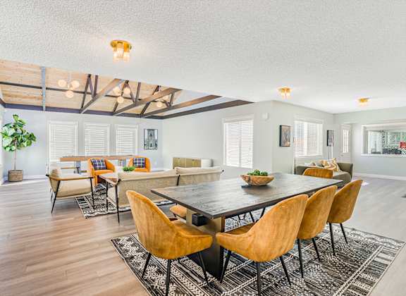 A large room with a table and a room with a shuffleboard table in the background
