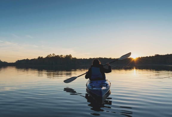 a person in a kayak on a lake at sunset