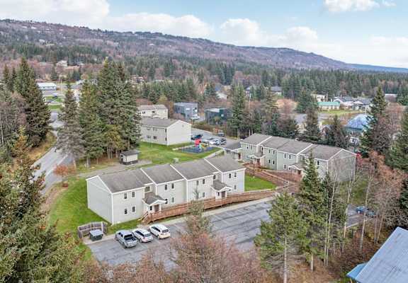 A large white building surrounded by trees and a parking lot.
