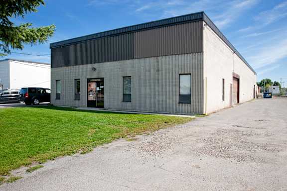 A large industrial building with a grey and white exterior and a parking lot in front.