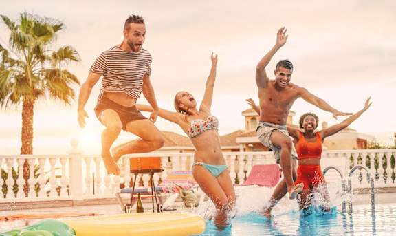 Four people jumping into a pool at Arbours at Hester Lake Apartments, Dade City
