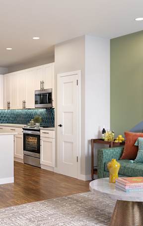 A modern kitchen with a bar area and a green couch.