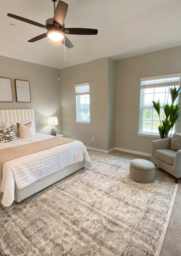 A bedroom with a large bed, a chair, and a rug.