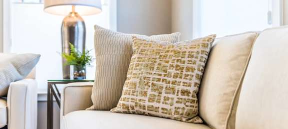 A white couch with a yellow and white pillow on it.
