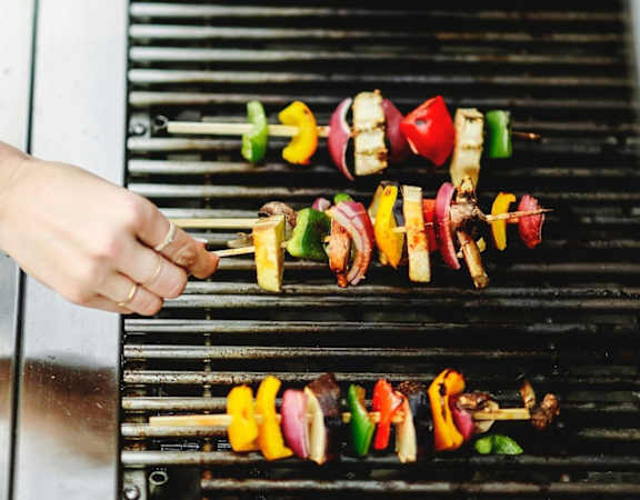 a hand holding a skewer of food on a grill at Hampton in Highland Apartments, Indiana, 46322