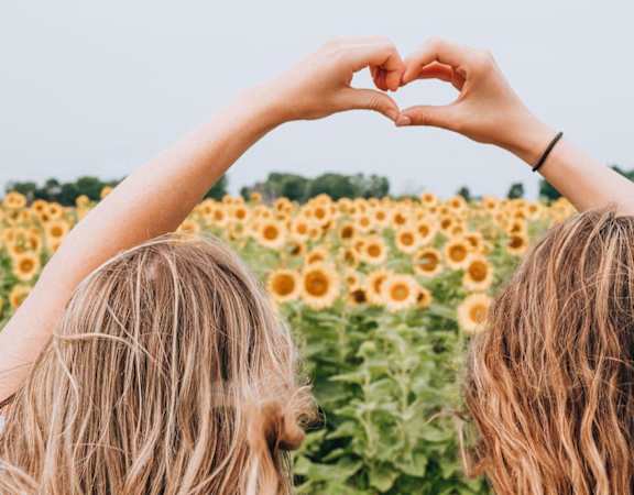 two girls in a field of sunflowers making a heart shape with their hands at Whitcomb Terrace Apartments, Merrillville