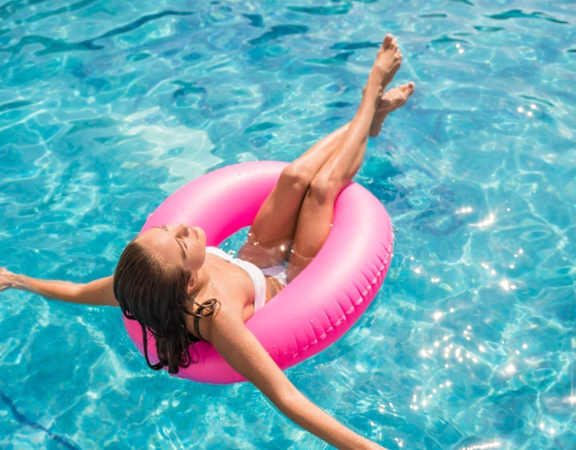 a young woman floating on a pink inner tube in a pool at Whitcomb Terrace Apartments, Merrillville, IN