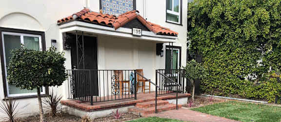 A white house with a red tile roof and a black gate.