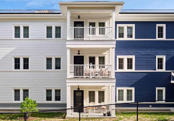 a picture of a three story apartment building with blue and white siding and a black door