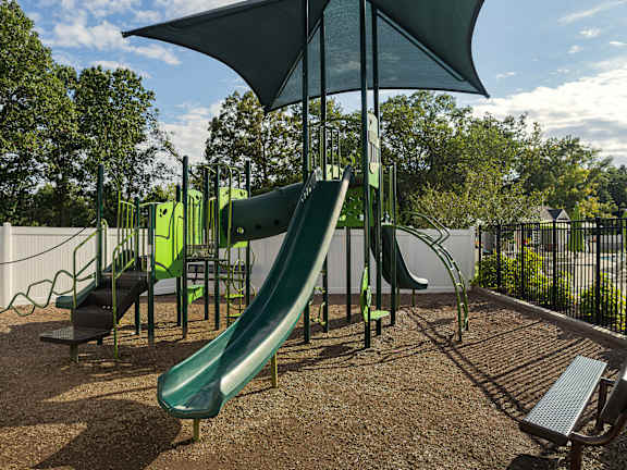 A playground with a green slide and a bench.