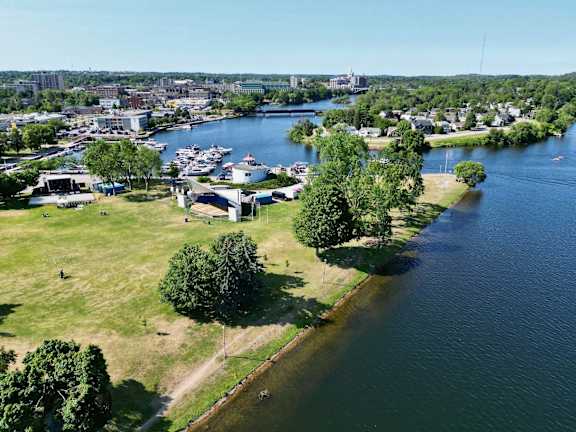 An aerial view of a park with a lake and a city in the background.