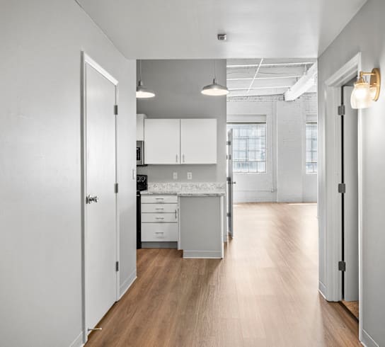 A kitchen with white cabinets and a wooden floor.