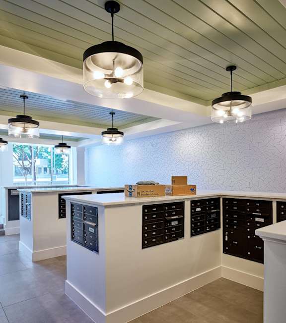 A kitchen with white counter tops and black drawers.
