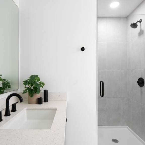 A white sink in a modern bathroom with a grey shower.