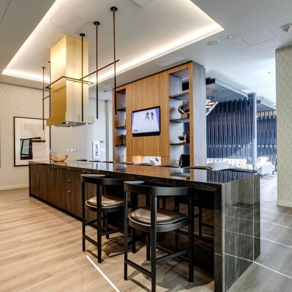 a kitchen with a marble counter top and black stools at Citizen on Jasper, Edmonton, Alberta, T5K 0P3