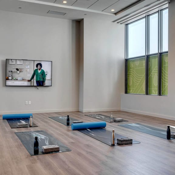 a yoga room with yoga mats on the floor and a tv on the wall at Citizen on Jasper, Edmonton, AB