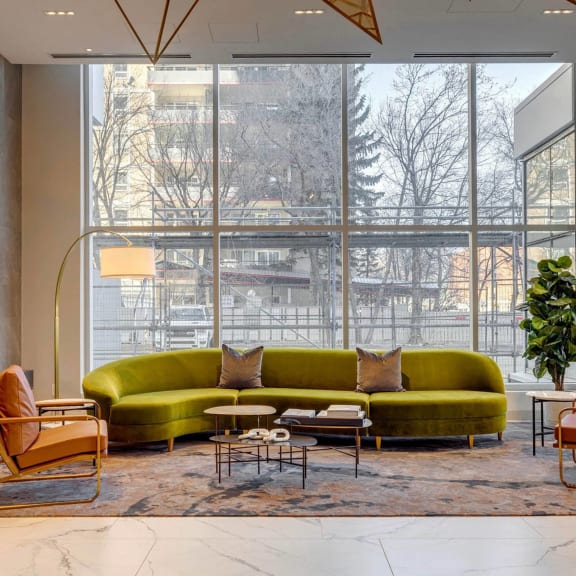 a living room with a green couch and a large window at Citizen on Jasper, Edmonton, Alberta