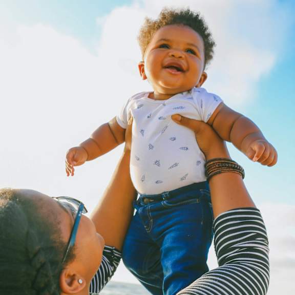 A woman lifts a baby up in the air.