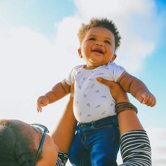 A woman lifts a baby up in the air.