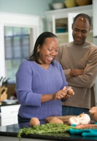 a man and woman laughing while preparing food in a kitchen at University Park, Azusa
