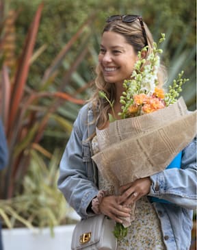 A woman is holding a bouquet of flowers and smiling.