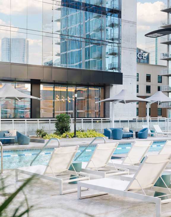A pool area with lounge chairs and umbrellas in front of a modern building.