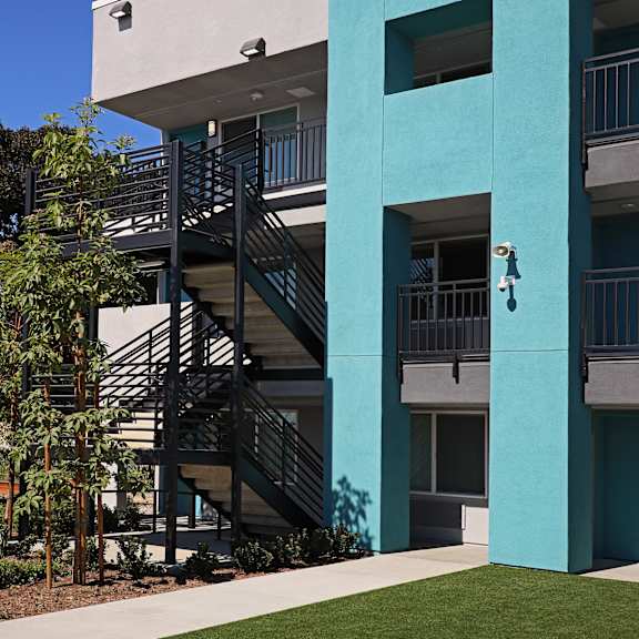 A white building with a balcony and a blue sky in the background.