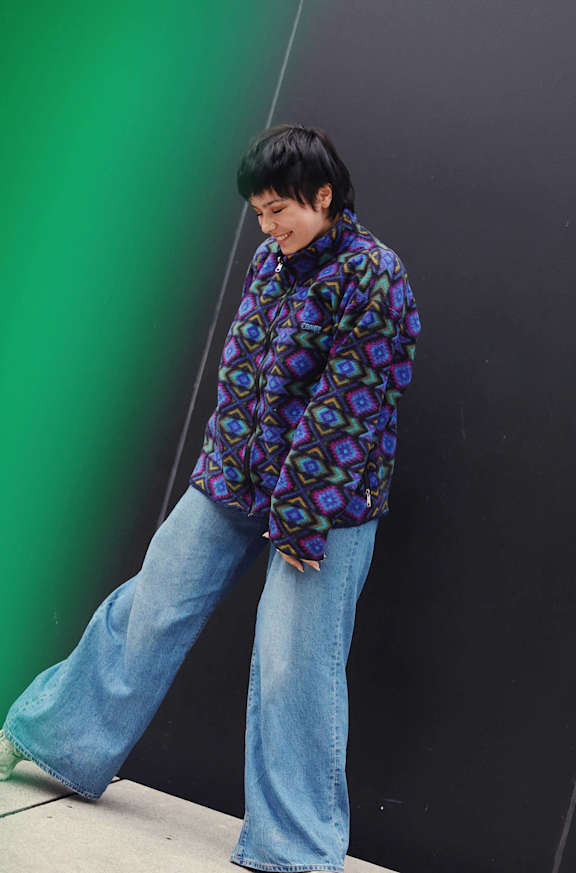 A person wearing a blue and purple patterned shirt and blue jeans.