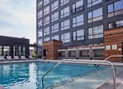 Thumbnail 1 of 8 - A swimming pool is surrounded by a wooden deck and lounge chairs.