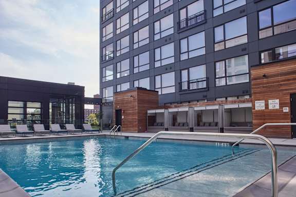 A swimming pool is surrounded by a wooden deck and lounge chairs.