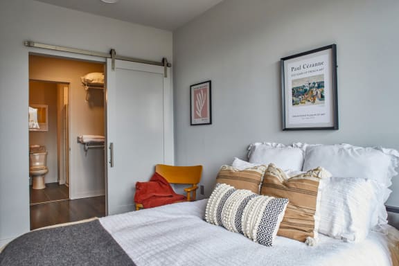 A bedroom with a bed, a chair, and a picture of Paul Cezanne on the wall at Sono Central in Norwalk, CT, 06854