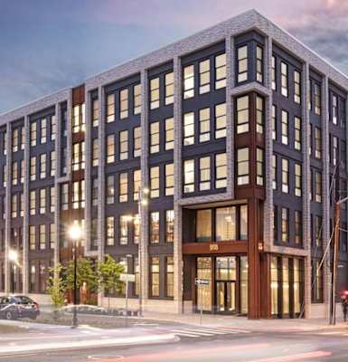 A modern multi-story building with a parking lot in front.