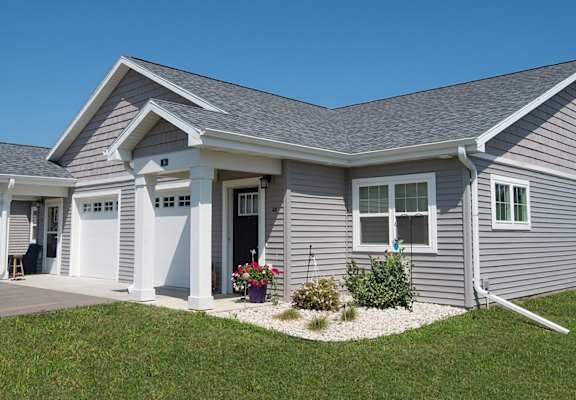 A grey house with a white door and windows.